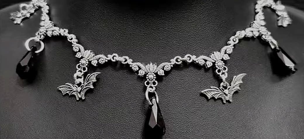 Silver bat necklace with black teardrop crystals on a display bust